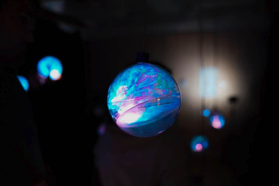 A dark image with a number of illuminated orbs hanging from the ceiling.